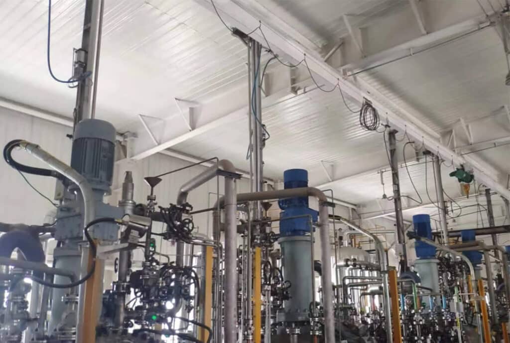 Pneumatic cylinder raising a cleaning mechanism above a chemical process vessel
