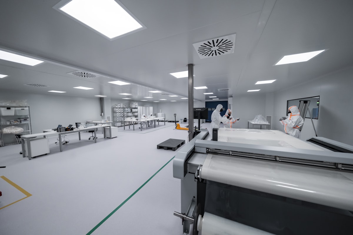 ผู้ปฏิบัติงานในสภาพแวดล้อม controlled cleanroom manufacturing พร้อมอุปกรณ์และวัสดุที่ป้องกันไว้